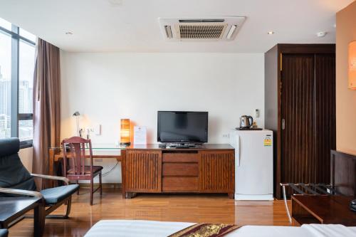 a living room with a tv and a desk and a refrigerator at Hotel Mermaid Bangkok in Bangkok