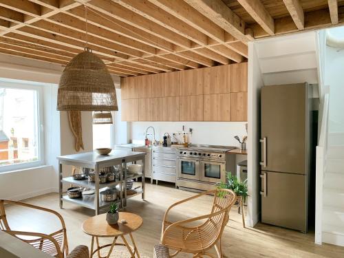 une cuisine avec une table, des chaises et un réfrigérateur dans l'établissement Mer nature, appartement spacieux by Les Filles du Bord de Mer, petite terrasse vue mer, à Port-en-Bessin-Huppain