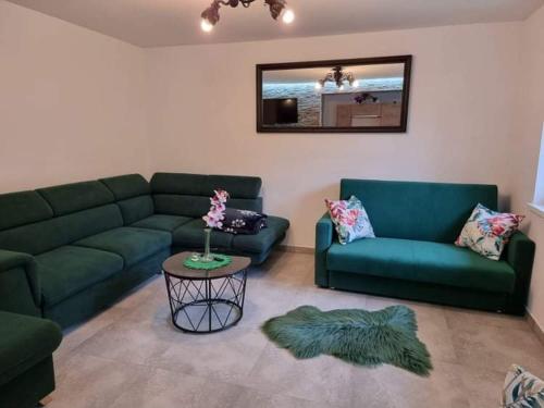 a living room with two green couches and a table at Sylwia Aparthouse - Biały Dunajec in Biały Dunajec