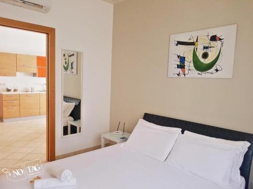 a bedroom with a white bed and a mirror at Colonna Rooms & apartment in Trani