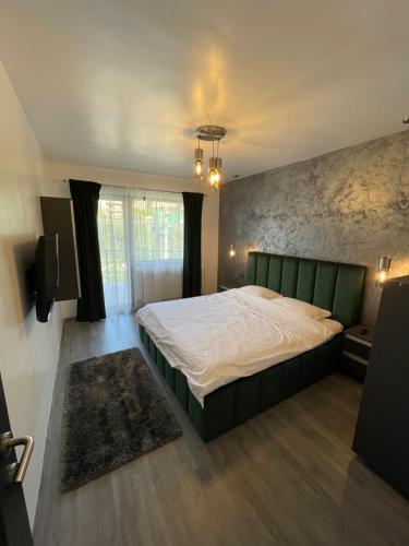una camera con un grande letto con testiera verde di Gray Apartments Busteni a Buşteni