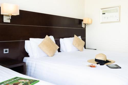 a hotel room with a bed with a hat on it at Mercure Maidstone Great Danes Hotel in Maidstone