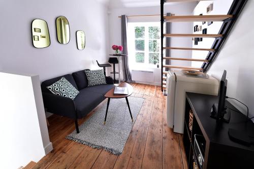 ein Wohnzimmer mit einer Couch und einer Treppe in der Unterkunft Le kocon, dans un écrin, le calme à la mer in Saint-Pair-sur-Mer