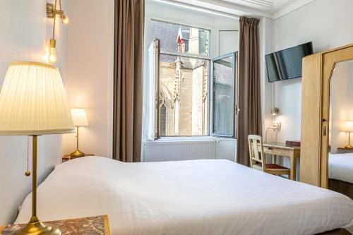 a hotel room with a white bed and a window at Hôtel Saint Maurice in Lille