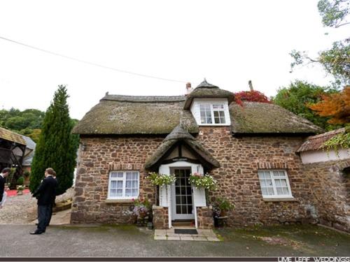 um homem parado em frente a uma casa de tijolos em Bickleigh Castle em Tiverton