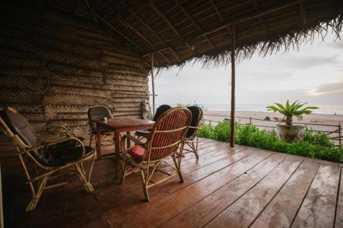 a table and chairs on a deck with the beach at The Village Agonda in Agonda