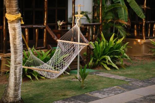 a hammock hanging from a palm tree in a garden at The Village Agonda in Agonda