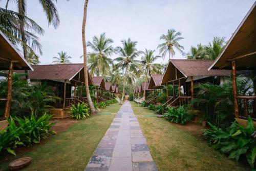 a path through the courtyard of a resort with palm trees at The Village Agonda in Agonda