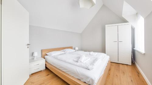 a white bedroom with a bed and a dresser at Apartamenty Sun & Snow Plac Neptuna in Międzyzdroje