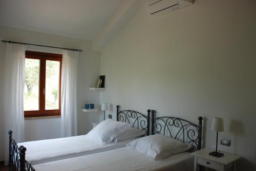 two beds in a white bedroom with a window at B&B Profumo delle Marche in Montefano