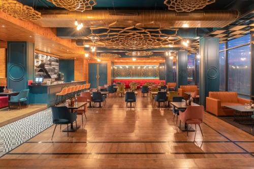 a restaurant with a bar and tables and chairs at Clarion Hotel Dehradun in Dehradun