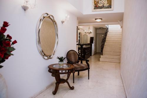 a hallway with a mirror and a chair and a table at Hotel Bela Kuka in Bitola