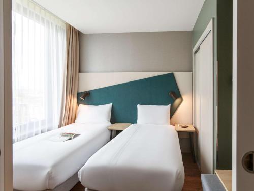 a hotel room with two beds and two lamps at Aparthotel Adagio London Stratford in London