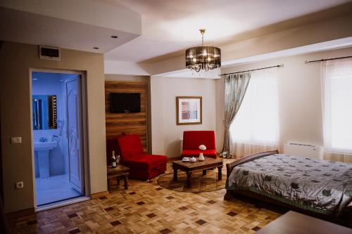 a bedroom with a bed and a red chair at Hotel Bela Kuka in Bitola