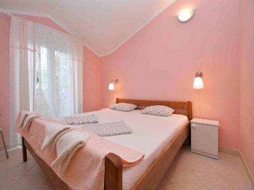 - une chambre avec un grand lit aux murs roses dans l'établissement Apartments Mila, à Murter