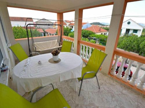 Biały stół i zielone krzesła na balkonie w obiekcie Apartments Mila w mieście Murter