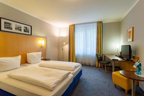 a hotel room with two beds and a desk at Best Western Waldhotel Eskeshof in Wuppertal