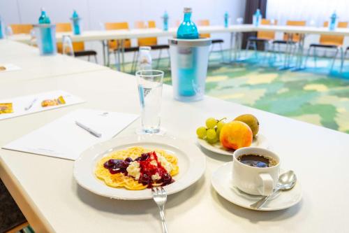 a table with a plate of food and a cup of coffee at Waldhotel Eskeshof in Wuppertal