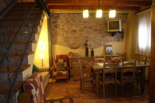 sala de estar con mesa de comedor y pared de piedra en Casa Rural Ca Lazaro, en Bot