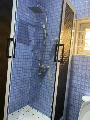 y baño con ducha de azulejos azules y aseo. en Tills Beach Resort, en Fete
