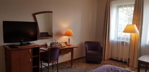 a hotel room with a desk with a television and a mirror at Hotel Amaryllis in Swarzędz