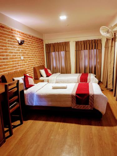 a bedroom with two beds and a brick wall at Hotel vintage Home in Bhaktapur