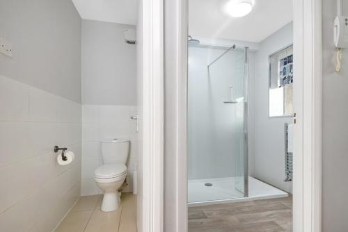 a bathroom with a toilet and a glass shower at Surbiton modern 2 bedroom flat with parking in Surbiton