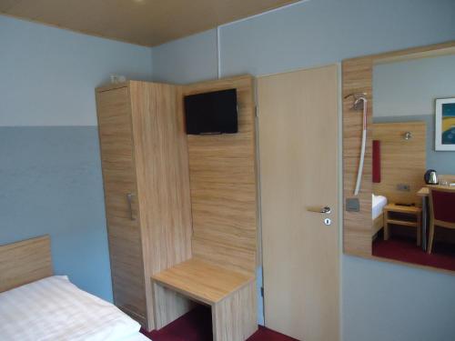a room with a bedroom with a bed and a tv at Hotel Garten in Bonn