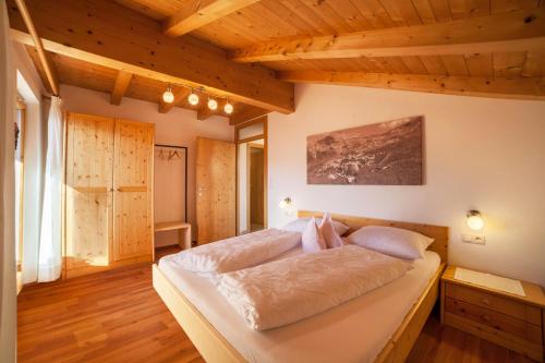 a large bed in a room with wooden ceilings at Tonigbauernhof Blumenwiese in Schenna