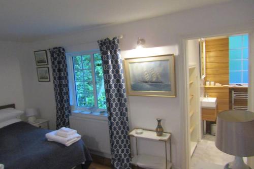 a bedroom with a bed and a window and a table at Lovely Spacious Cottage Near The Coast in St Austell