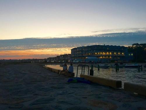 two people sitting on the beach at sunset at 1860's Colonial House Near Downtown and Beaches! in Madison