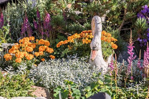 a garden of flowers with a statue in the middle at Tonigbauernhof Enzian in Schenna