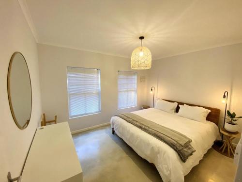 a bedroom with a large bed and a mirror at Daisy Cottage in Hermanus