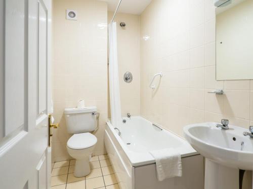 a white bathroom with a toilet and a sink at The Woodfield Hotel in Clifden