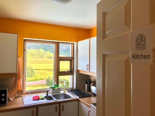 a kitchen with a sink, refrigerator and window at Paradise Cave Hostel & Guesthouse in Seljaland