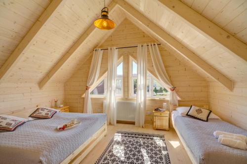 two beds in a attic room with a window at Domki letniskowe w centrum Tylicza in Tylicz