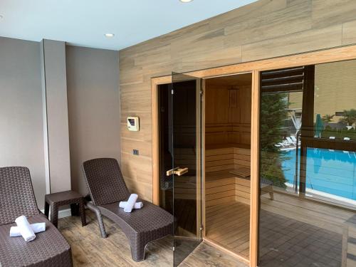 a room with two chairs and a glass door with a pool at Neptun Palace Kvariati in Kvariati