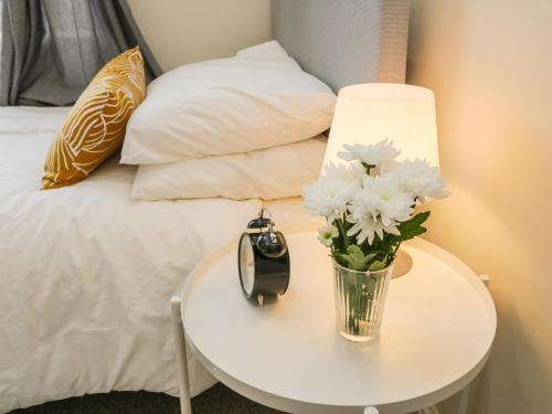 a table with a lamp and a vase with flowers on it at 24 Baxtergate in Whitby