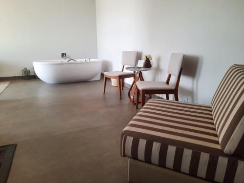 a bathroom with a tub and a chair and a bath tub at Capão do Cerrado Pousada e Spa in Itabirito