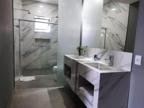 a white bathroom with two sinks and a shower at Capão do Cerrado Pousada e Spa in Itabirito