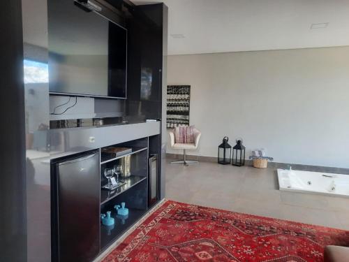 a living room with a television and a red rug at Capão do Cerrado Pousada e Spa in Itabirito