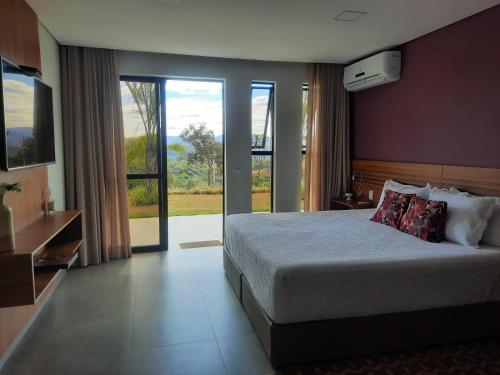 a bedroom with a large bed and a large window at Capão do Cerrado Pousada e Spa in Itabirito