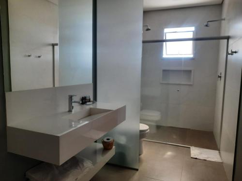 a white bathroom with a sink and a toilet at Capão do Cerrado Pousada e Spa in Itabirito