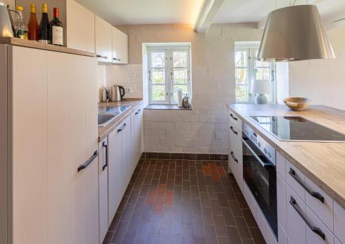 a kitchen with white cabinets and a brown tile floor at Das alte Zollhaus in Schülp