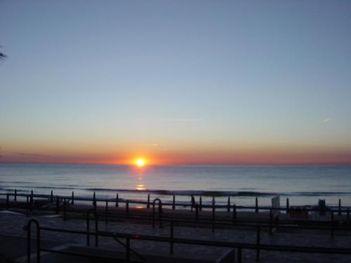 a sunset on the beach with the sun setting at Hotel Beau Rivage in Alassio