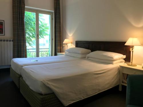 a bedroom with a large white bed with a window at Hotel Beau Rivage in Alassio