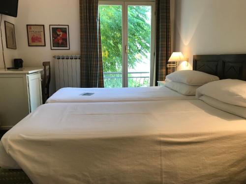 a large white bed in a bedroom with a window at Hotel Beau Rivage in Alassio