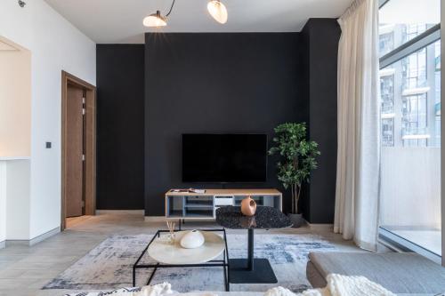 - un salon avec un mur noir et une télévision dans l'établissement EDEN'S Homes & Villas - Millennium Atria Residences, à Dubaï