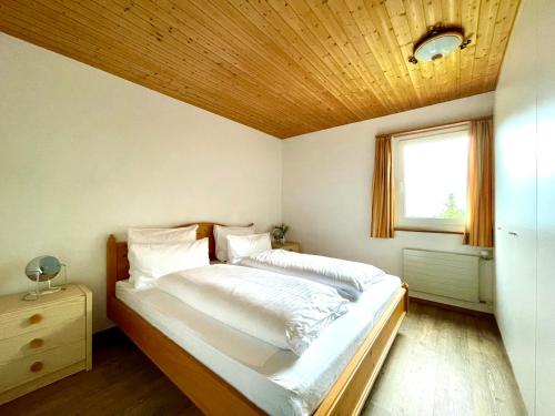 a bedroom with a large bed with a wooden ceiling at Alpenlodge Val Gronda in Obersaxen