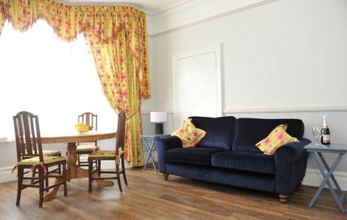 a living room with a blue couch and a table at Beechurst Serviced Apartments in Cheltenham
